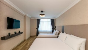 Una habitación de hotel con una cama grande, un televisor montado en la pared y una ventana con cortinas.