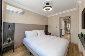 A modern hotel room with a large bed, a bedside table with a lamp, an air conditioning unit, and a ceiling light fixture. - Khotel Temel Chorlu (Çorlu)