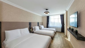 Habitación de hotel con dos camas, un televisor de pantalla plana en la pared y una ventana con cortinas.
