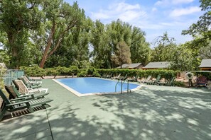 A swimming pool with lounge chairs and a deck area, surrounded by trees and a building. - Cozy Cabins with Modern Amenities and Rustic Charm in Colorado Springs (Colorado Springs)