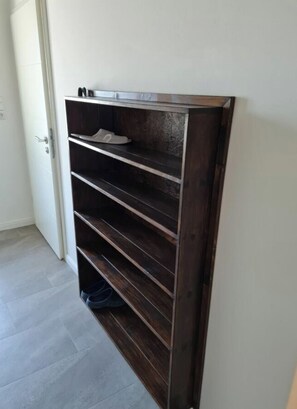 A dark wooden shelf unit with multiple compartments, a door to the left, and a tiled floor. - Holiday Home in Walkenried With Barbecue (Walkenried)