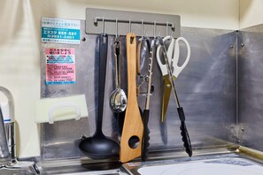 A kitchen area with various utensils hanging on a rack, including a ladle, a wooden spoon, and a pair of scissors.