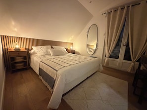 A bedroom with a bed, bedside tables, a nightstand, a mirror, and curtains. - Vrbo Property (Gertwiller)
