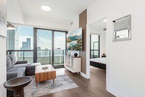 A modern apartment with a large balcony, a sofa, a coffee table, and a painting. - Sunset Retreat | 2BR/2BA | CN Tower View + Parking (Mississauga)