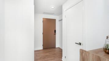 A hallway with a wooden floor, white walls, and a door at the end.