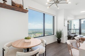 A modern interior with a large window, a round table, and seating. - Sunset Retreat | 2BR/2BA | CN Tower View + Parking (Mississauga)