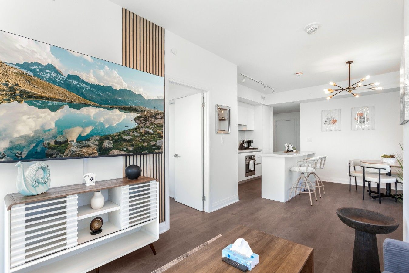 Un interior moderno con un cuadro de paisaje grande, una zona de cocina y un espacio para comer.