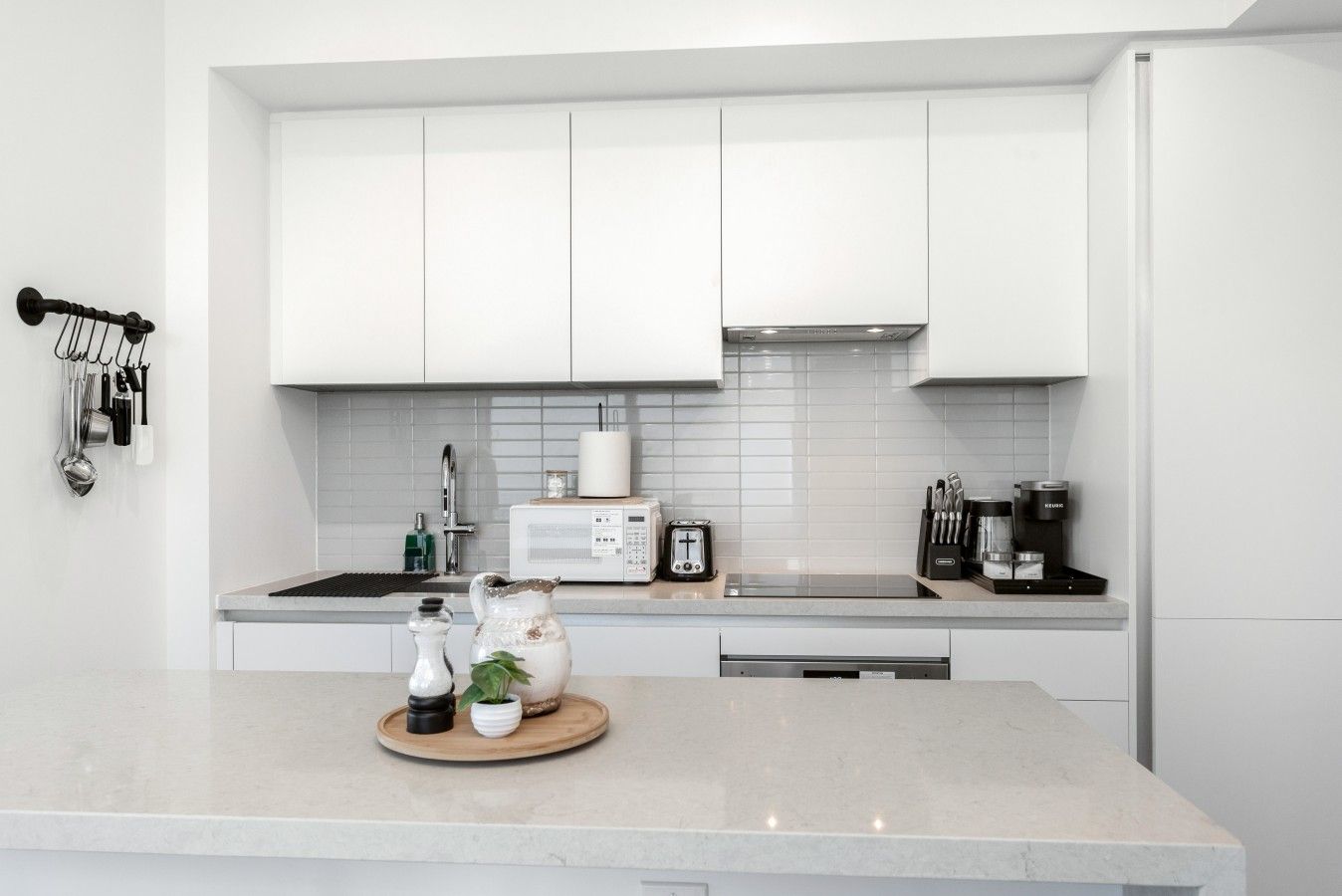 A modern kitchen with white cabinets, a microwave, a toaster, and a coffee maker.