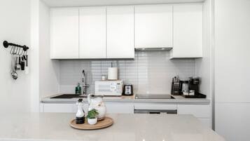 A modern kitchen with white cabinets, a microwave, a toaster, and a coffee maker.