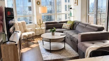 A modern living room with a sofa, coffee table, and a TV stand with a bookshelf.