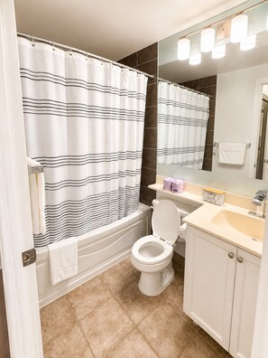 A bathroom with a bathtub, toilet, and sink. - High-Rise 3BR Oasis | Free Parking | City Views (Mississauga)