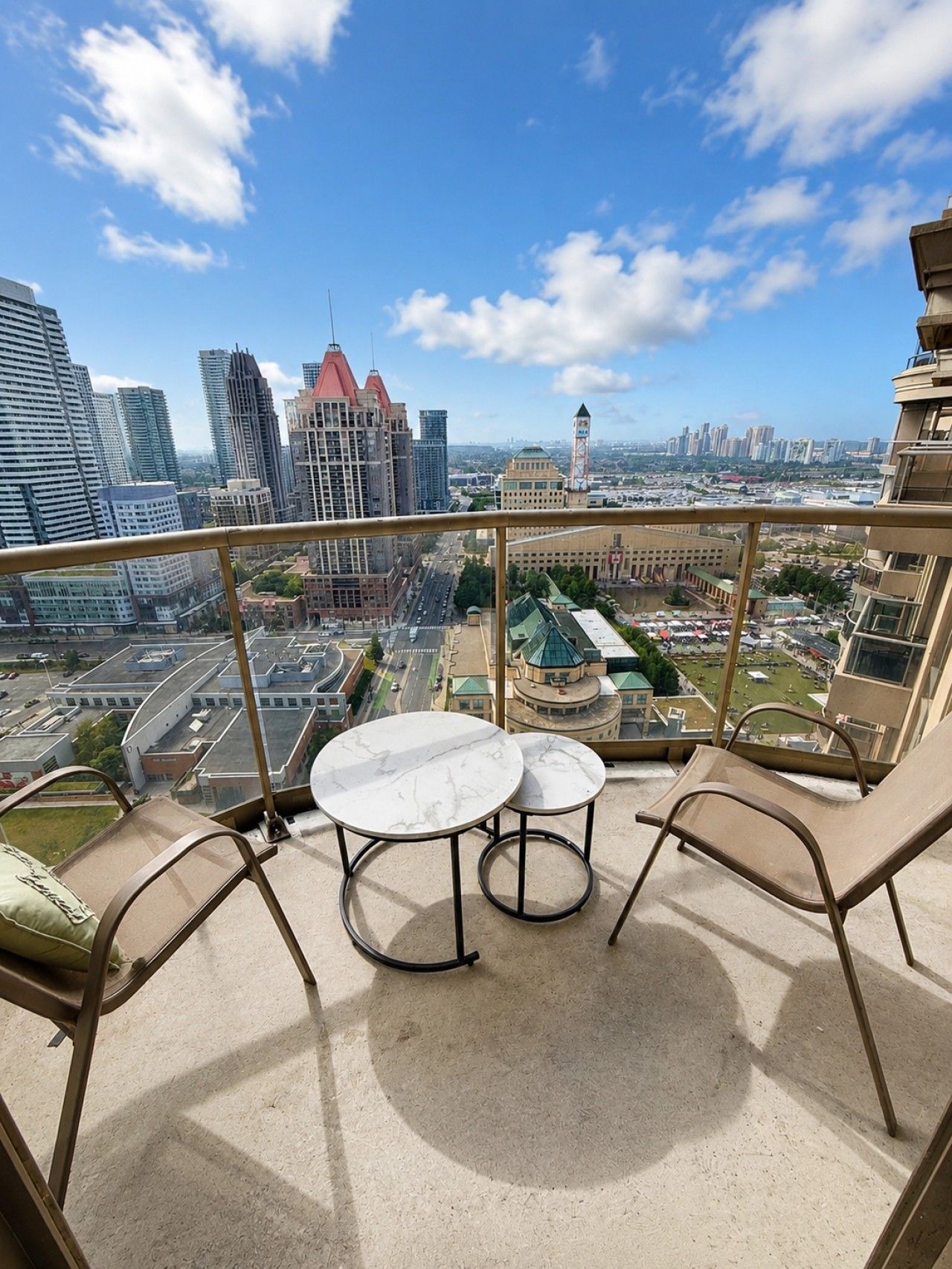 A balcony with a table and chairs, offering a city view.