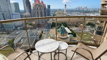 A balcony with a table and chairs, offering a city view.