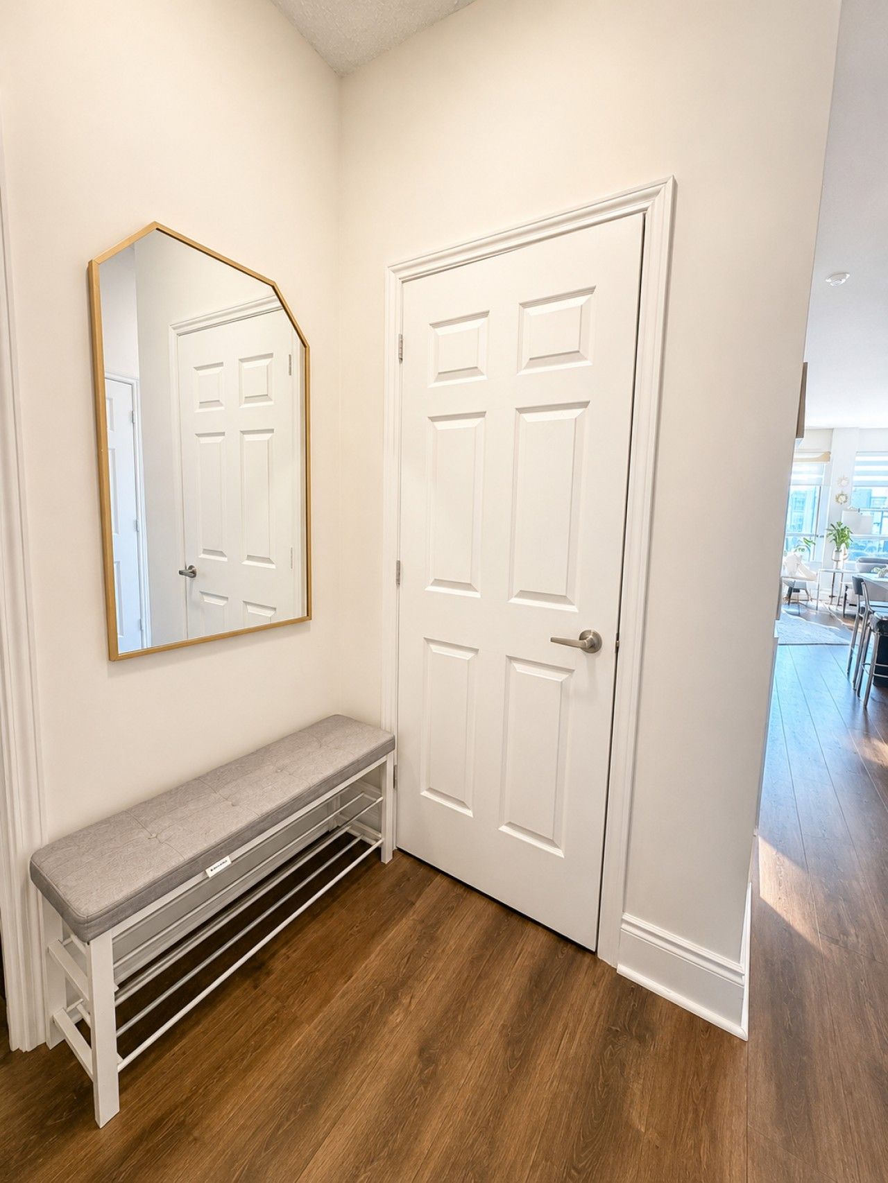 A hallway with a bench, a door, and a mirror.