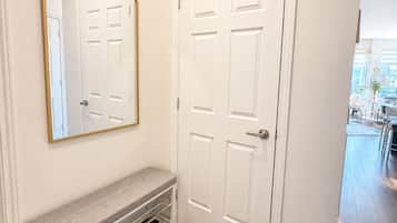 A hallway with a bench, a door, and a mirror.