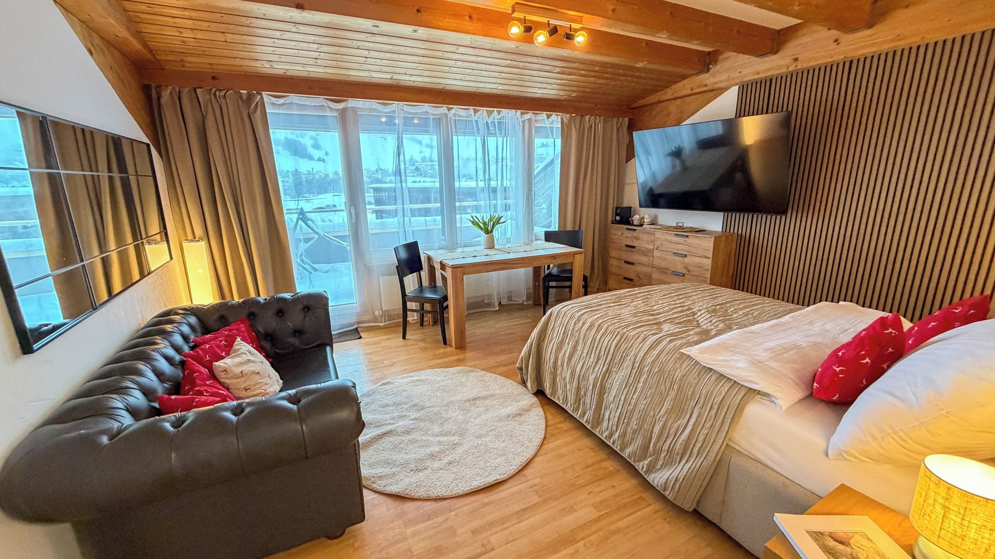 A cozy room with a bed, a sofa, a desk, and a TV.