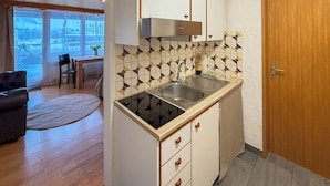 A compact kitchen with a built-in sink, a stove, and a small countertop. - Plan-B Stay (Samedan)