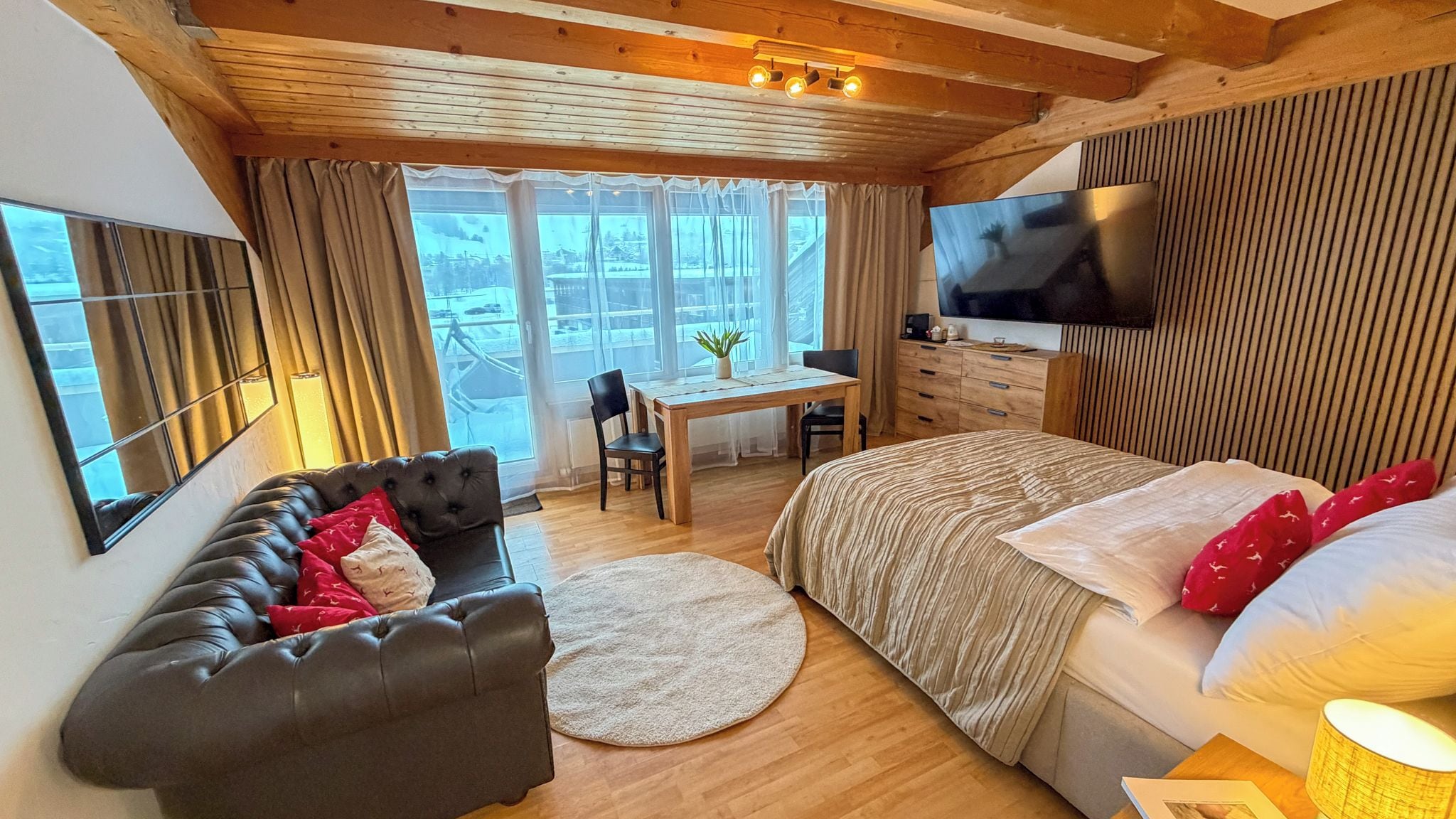 Una habitación acogedora con una cama, un sofá, un escritorio y un televisor.