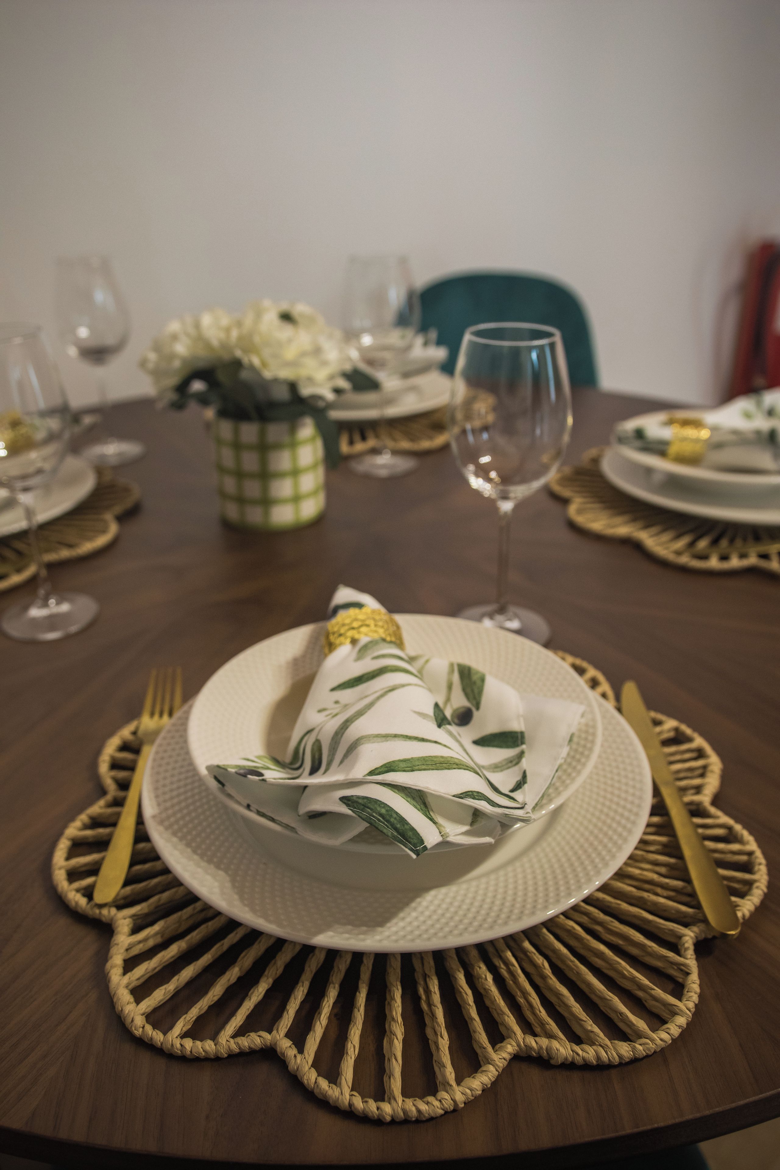 A round dining table with a placemat, a folded napkin, and cutlery.