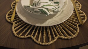 A round dining table with a placemat, a folded napkin, and cutlery. - Welcome to Entre Raízes, a warm and peaceful place (Remédios)
