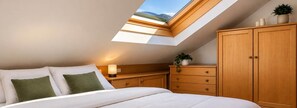 A bedroom with a skylight, a bed, a nightstand, a dresser, and a potted plant. - Oria Dolomites Stay (Alba)
