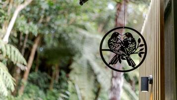 A circular metal ornament with a bird design, hanging near a window with a blurred natural background.