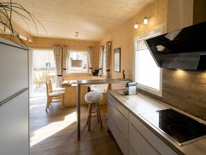 A modern kitchen with wooden cabinets, a stainless steel stove, and a bar area. - One-bedroom Cabin (Sankt Georgen am Kreischberg)