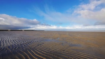 Une plage avec des ondulations dans le sable et un ciel dégagé.