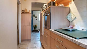 Een keuken met houten kastjes, een aanrecht en een kookplaat.