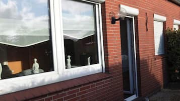 Une maison en briques avec une grande fenêtre et une porte plus petite, toutes deux dotées de cadres blancs.