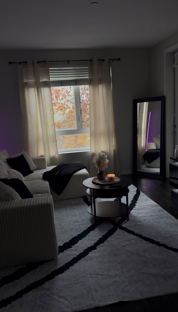 Ein modernes Wohnzimmer mit einer Couch, einem runden Tisch mit einer Vase und einem großen Spiegel.