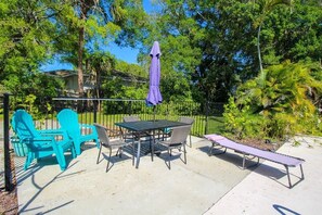 An outdoor patio with a table and chairs, a bench, and a purple umbrella. - Private 3BR Pool Home | Pet Friendly | Sleeps 8 (Bradenton)