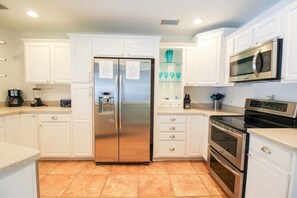 A modern kitchen with white cabinetry, stainless steel appliances, and a tiled floor. - Private 3BR Pool Home | Pet Friendly | Sleeps 8 (Bradenton)