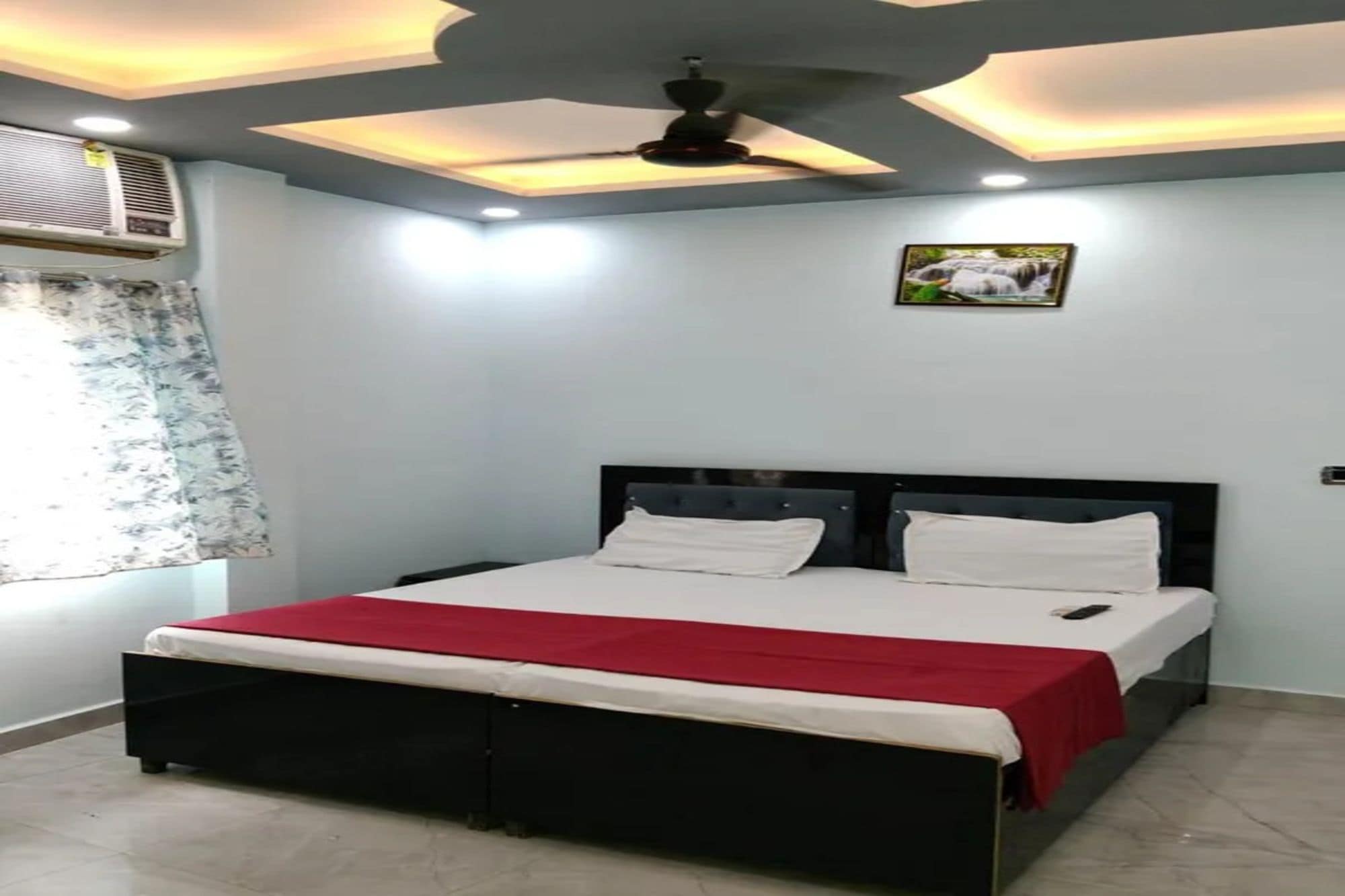 Un dormitorio con una cama, ventilador de techo y una ventana con cortinas.