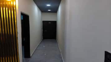 Un pasillo estrecho con una puerta marcada '02' al final, que conduce a una habitación oscura.