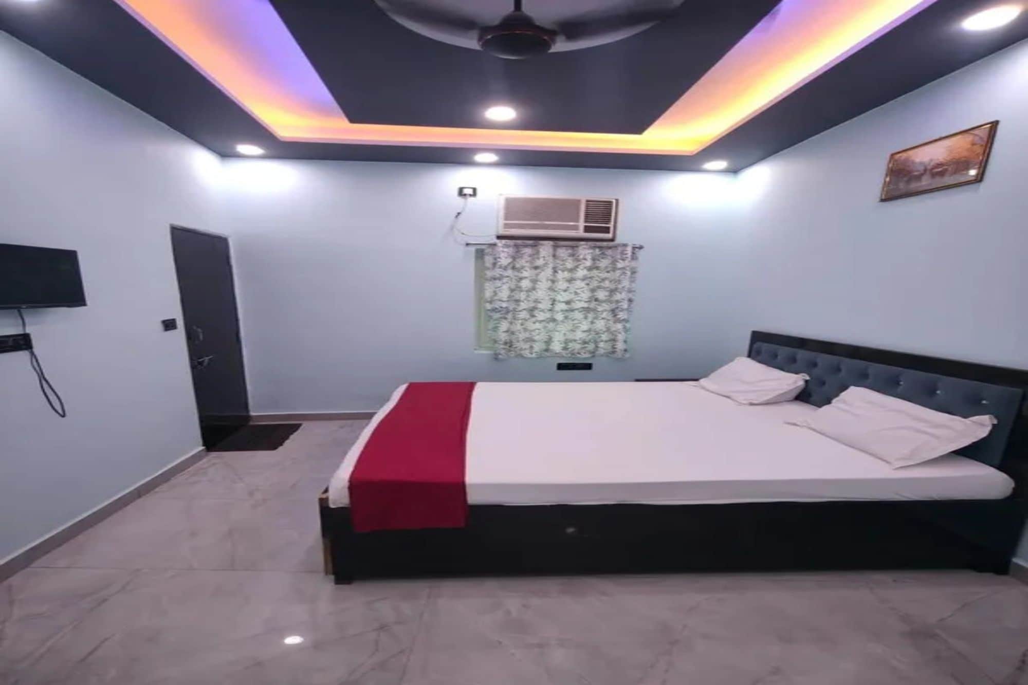 Une chambre à coucher comprenant un lit, un ventilateur de plafond, des spots encastrés, un appareil de climatisation et un téléviseur.