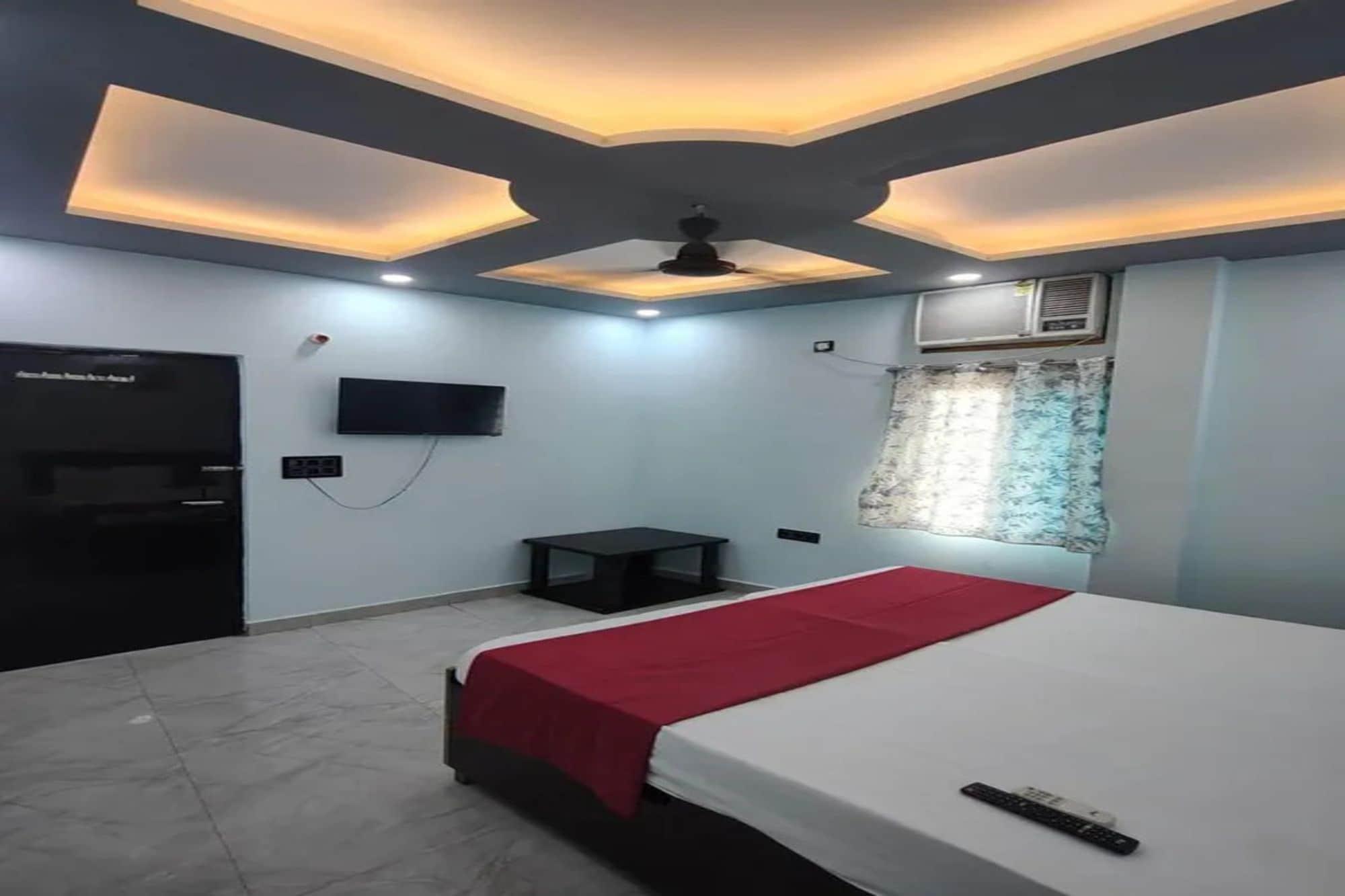 Habitación de hotel con cama, televisión, una mesita y un ventilador de techo.