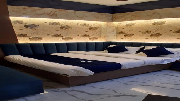Une chambre à coucher moderne avec un lit, une tête de lit rembourrée en tissu bleu et un mur décoratif orné de motifs floraux.