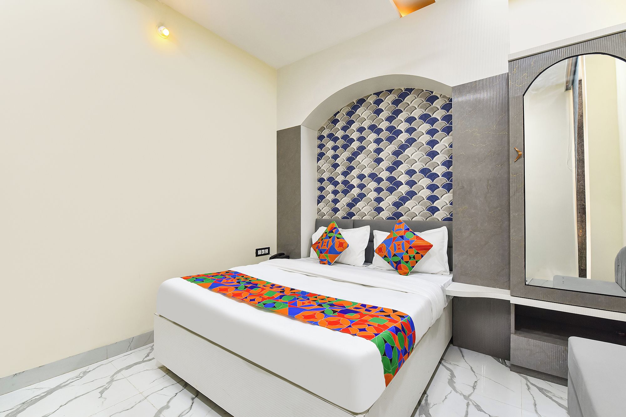 Una habitación de hotel con una cama, un espejo grande y un diseño decorativo en la pared.
