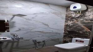 Une salle de bain avec un mur en marbre, une douche, des toilettes et un sèche-mains.