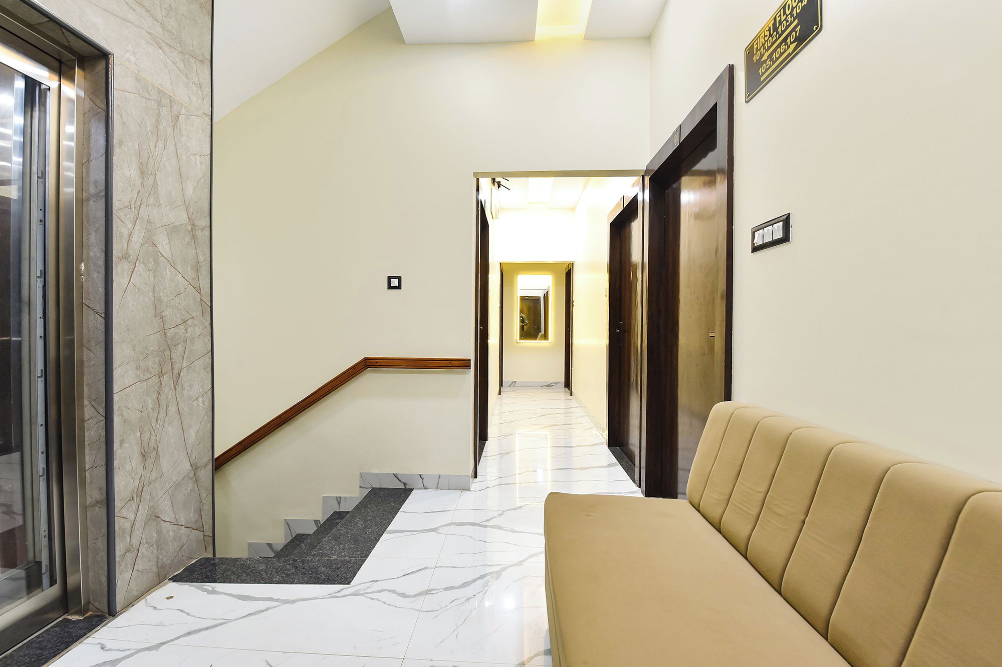 Un vestíbulo de hotel con una escalera de mármol, un sofá y una mesa de recepción.