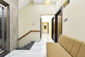 A hotel lobby with a marble staircase, a sofa, and a reception desk. - Fabhotel B1 (Indore)