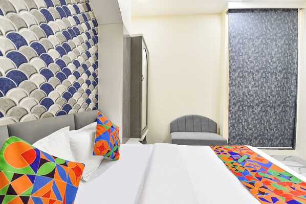 Una habitación de hotel con cama, almohadas, una silla y ventana con vistas.