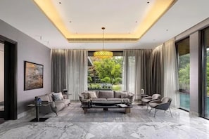 A modern living room with a marble floor, a sofa set, a coffee table, and a large window with curtains. - Fabhotel Vajra Residency (Mancherial)