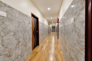 A hallway with marble walls, wooden flooring, and a door with a geometric design.