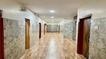Un couloir doté d’un sol en marbre, avec des portes de part et d’autre, et un couloir central menant à une pièce.
