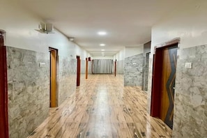 A hallway with marble flooring, doors on both sides, and a central corridor leading to a room. - Fabhotel Vajra Residency (Mancherial)