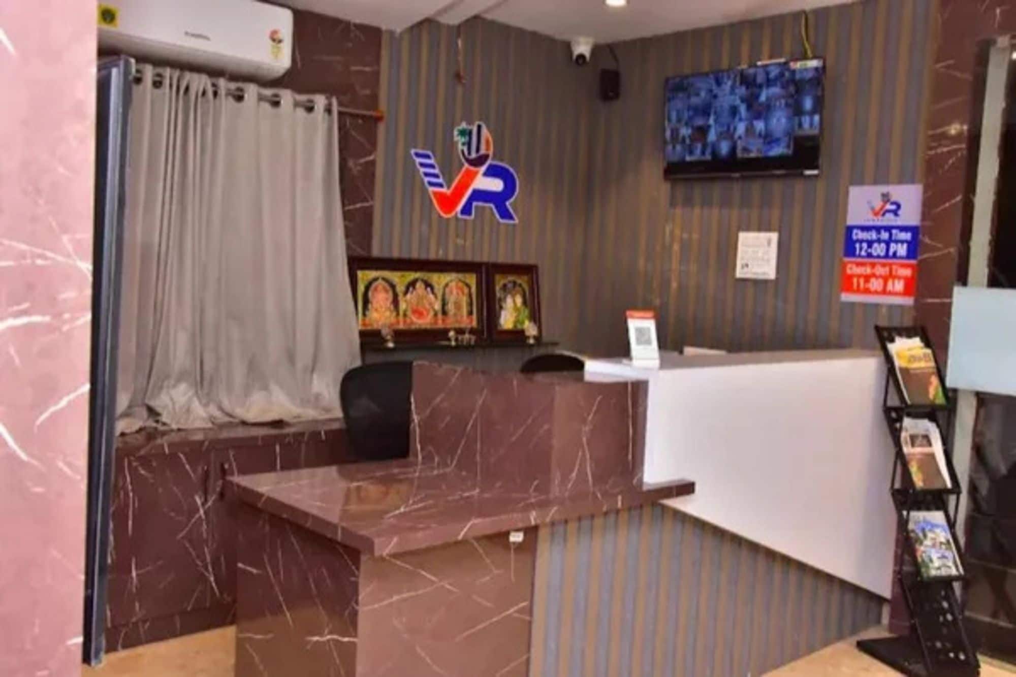 Una recepción con encimera de mármol, un televisor montado en la pared y un cartel de registro de entrada y salida.