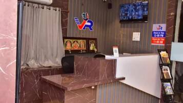 Una recepción con encimera de mármol, un televisor montado en la pared y un cartel de registro de entrada y salida.