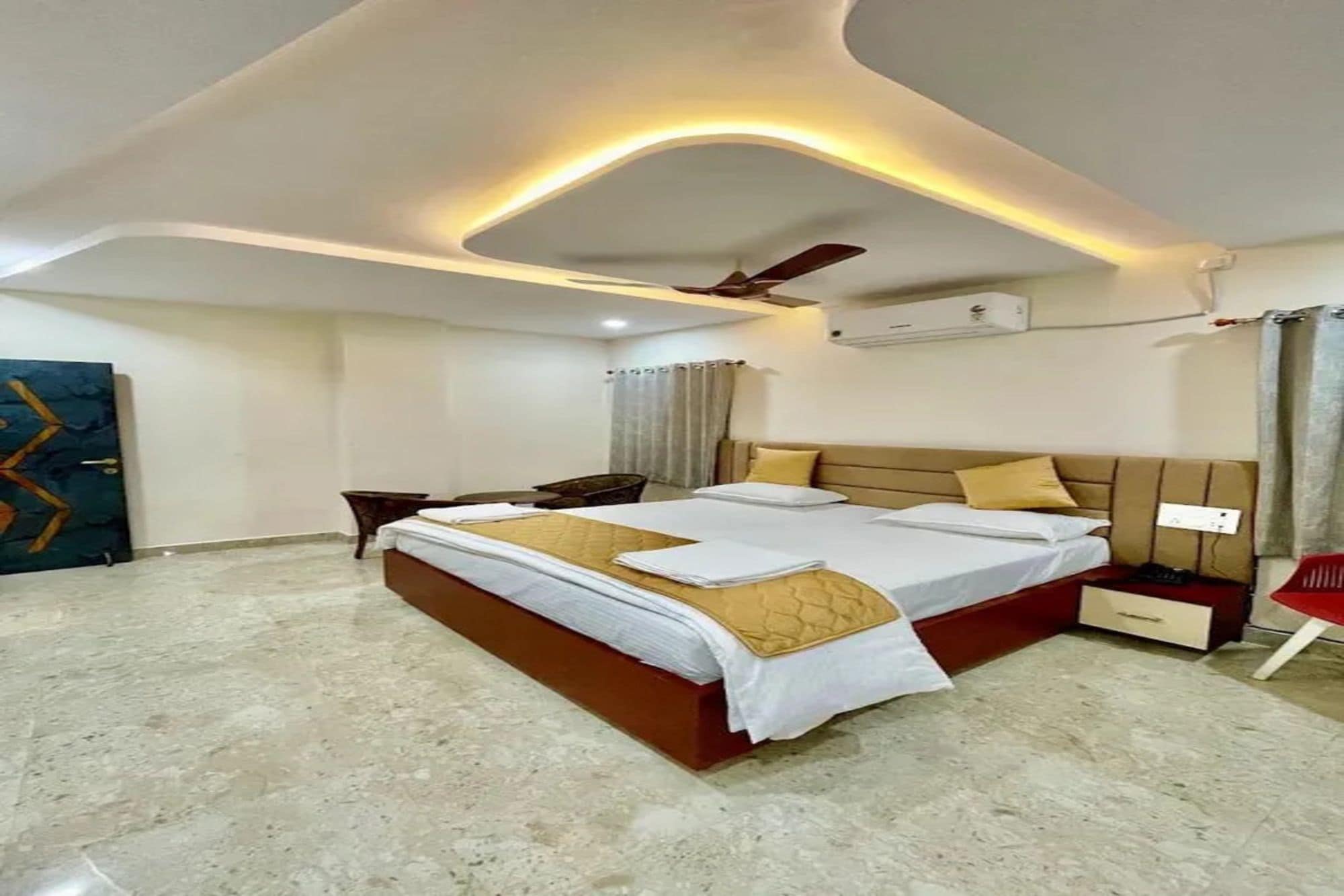 A modern hotel room with a large bed, a ceiling fan, and a flat-screen TV.